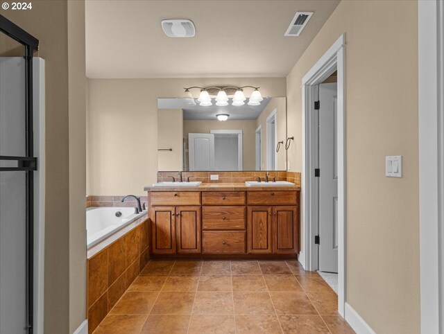 bathroom featuring tile patterned flooring, tiled bath, and vanity