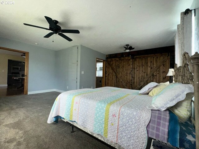 bedroom with carpet, ceiling fan, and a barn door