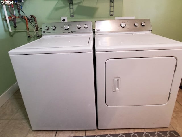 clothes washing area featuring light tile patterned floors and washing machine and dryer