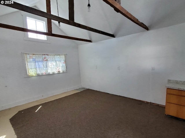 spare room featuring beamed ceiling, dark colored carpet, and high vaulted ceiling