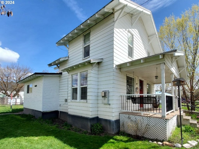 back of house featuring a porch and a yard