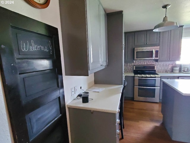 kitchen featuring backsplash, dark hardwood / wood-style flooring, stainless steel appliances, and hanging light fixtures