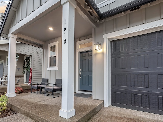 doorway to property with a garage, covered porch, and board and batten siding