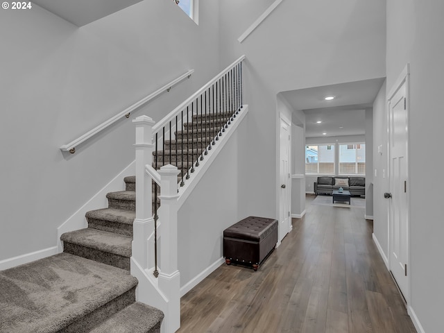 stairs with wood-type flooring and a high ceiling