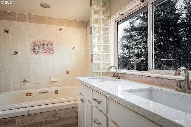 bathroom with tile walls, vanity, and a relaxing tiled tub