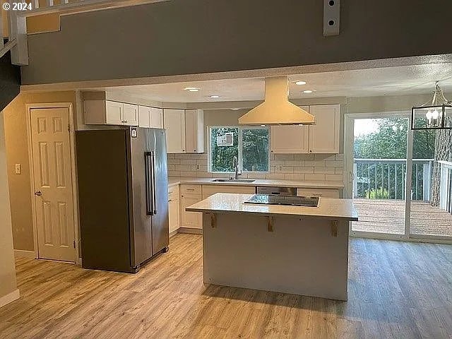 kitchen featuring white cabinetry, stainless steel refrigerator, and plenty of natural light