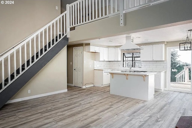 kitchen with white cabinets, tasteful backsplash, a breakfast bar area, a kitchen island, and light hardwood / wood-style floors