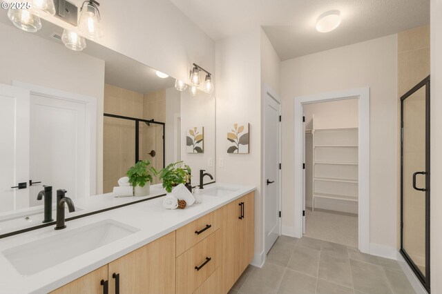 full bath with a walk in closet, tile patterned flooring, a stall shower, and a sink