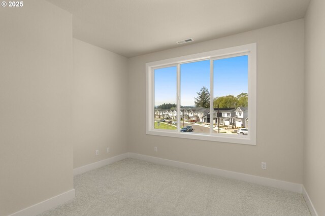 carpeted empty room with visible vents and baseboards