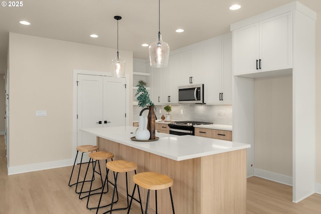 12040 SW Trask St Unit Lt96, Beaverton, OR 97007 - kitchen featuring appliances with stainless steel finishes, light wood-style flooring, backsplash, baseboards, and white cabinetry