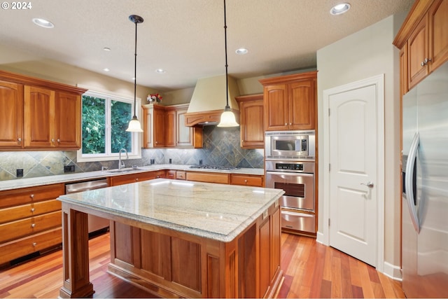 kitchen with decorative light fixtures, stainless steel appliances, sink, and a kitchen island