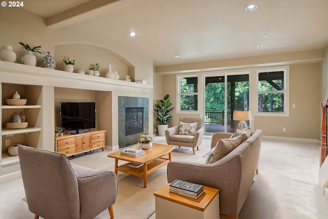 carpeted living room featuring beam ceiling and a tiled fireplace