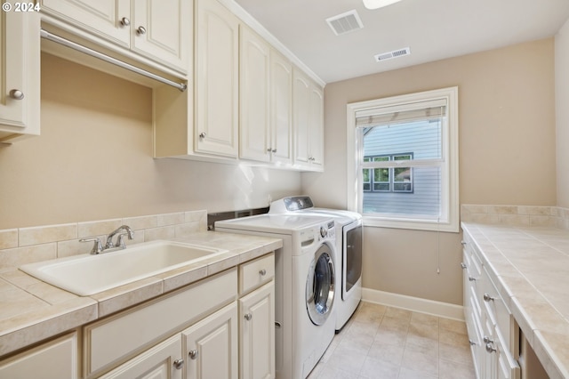 laundry area with cabinets, sink, and washing machine and dryer