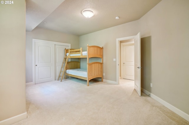 unfurnished bedroom with light colored carpet, a textured ceiling, and a closet