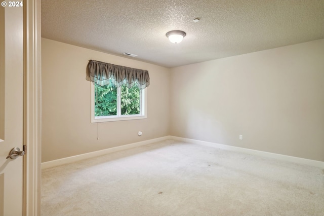 unfurnished room with light carpet and a textured ceiling