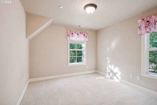 unfurnished room with vaulted ceiling, a textured ceiling, and carpet flooring