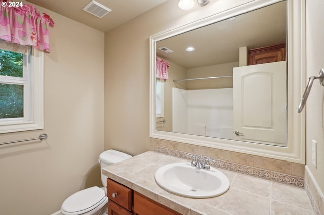 bathroom featuring walk in shower, vanity, toilet, and tile patterned floors