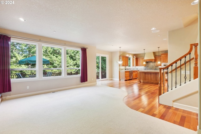 unfurnished living room featuring light hardwood / wood-style flooring and a textured ceiling