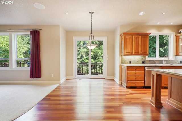 kitchen with sink, tasteful backsplash, decorative light fixtures, light hardwood / wood-style flooring, and dishwasher