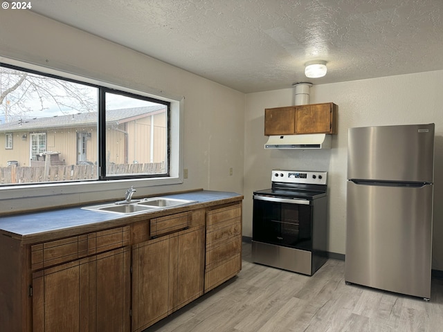 kitchen featuring refrigerator, exhaust hood, range, sink, and light hardwood / wood-style floors