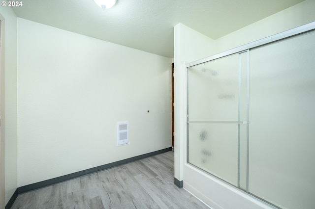 bathroom with shower / bath combination with glass door, visible vents, baseboards, and wood finished floors