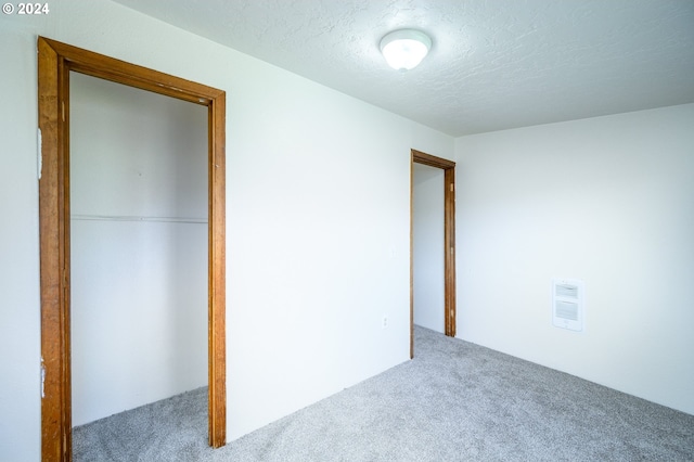 unfurnished bedroom with a closet, a textured ceiling, and carpet floors