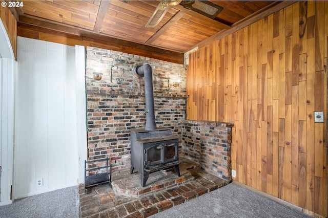 room details featuring wood walls, carpet flooring, a wood stove, and wooden ceiling