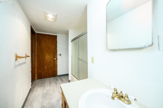 bathroom with wood-type flooring, vanity, and a shower with shower door