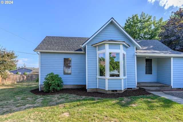 view of front of property with a shingled roof, a front yard, and fence