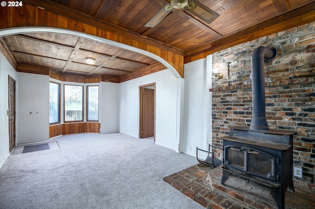 living room with ceiling fan, a wood stove, brick wall, and wooden ceiling