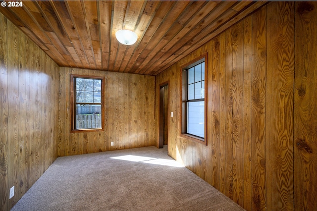 carpeted empty room with wood ceiling and wooden walls