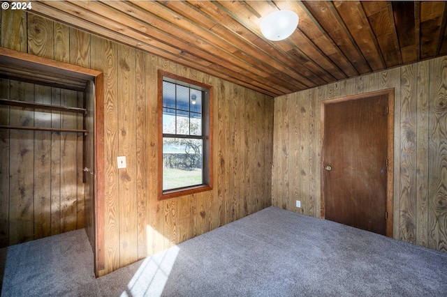 empty room featuring wood ceiling, wood walls, and carpet flooring