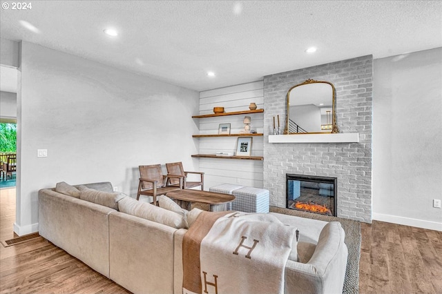 living room with a textured ceiling, a fireplace, and light hardwood / wood-style flooring