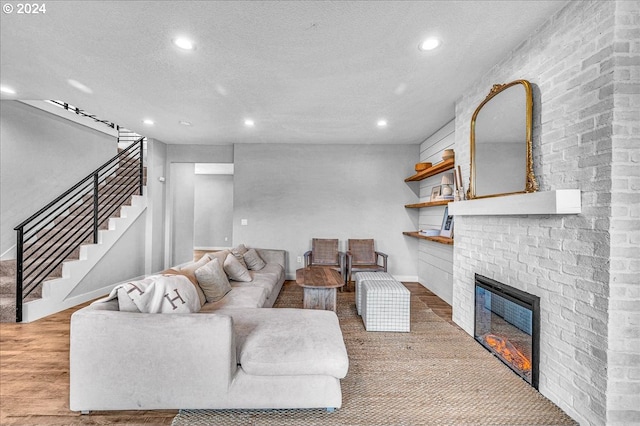 living room with a fireplace, a textured ceiling, and light hardwood / wood-style floors