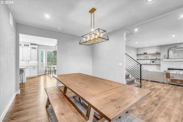 dining room featuring light hardwood / wood-style floors, a textured ceiling, and a brick fireplace