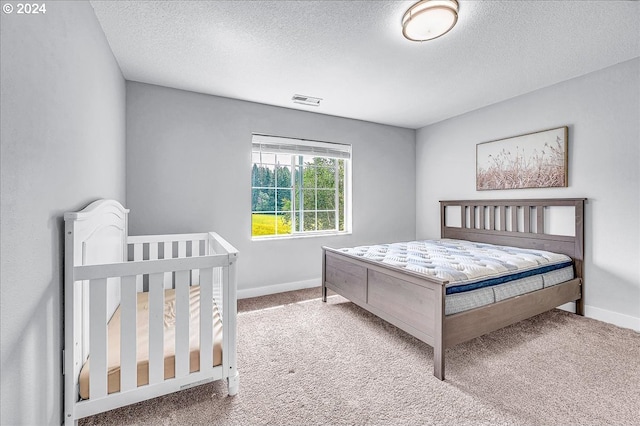 bedroom featuring carpet, a textured ceiling, and a nursery area