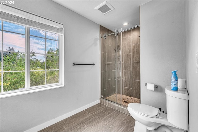 bathroom featuring walk in shower, a healthy amount of sunlight, and toilet