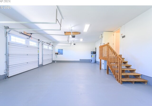 garage with secured water heater, a garage door opener, and electric panel