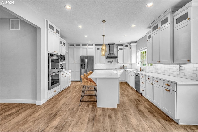 kitchen with a center island, white cabinets, stainless steel appliances, and custom exhaust hood