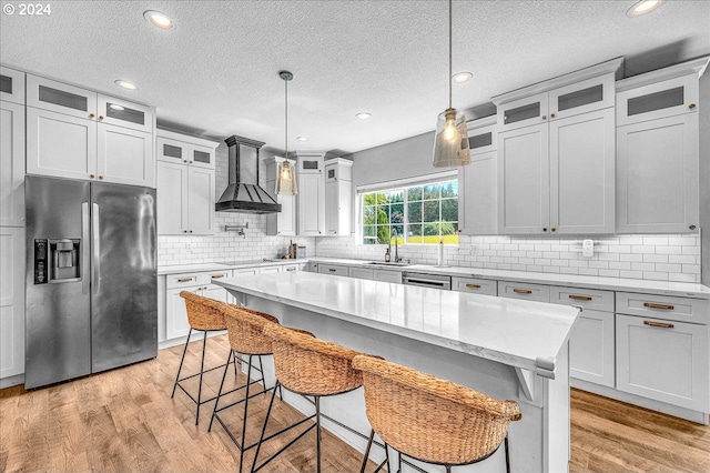 kitchen with decorative light fixtures, a center island, a kitchen bar, and stainless steel appliances