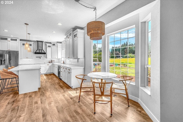 kitchen featuring white cabinets, light wood-type flooring, a center island, and decorative light fixtures