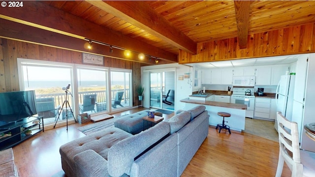 living room featuring beam ceiling, light wood-type flooring, wooden ceiling, and sink