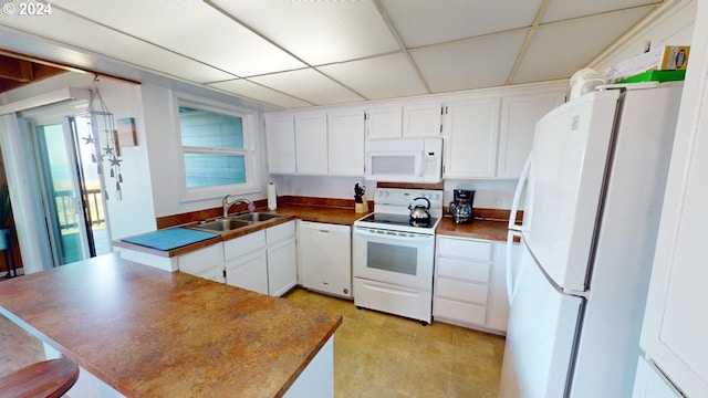 kitchen with a drop ceiling, white cabinetry, white appliances, and sink