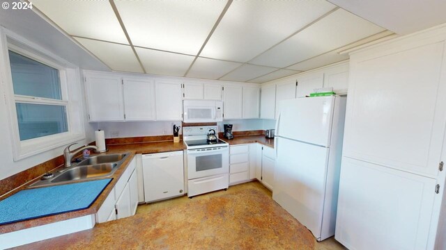 kitchen featuring white appliances, white cabinetry, a drop ceiling, and sink