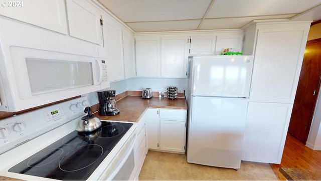 kitchen featuring a drop ceiling, white cabinets, white appliances, and light wood-type flooring