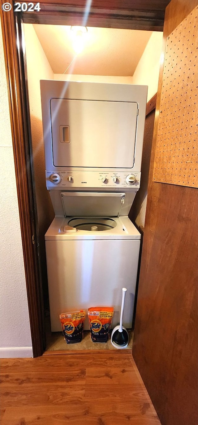 laundry room featuring hardwood / wood-style flooring and stacked washer and dryer