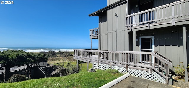 exterior space featuring a balcony, a yard, and a deck with water view