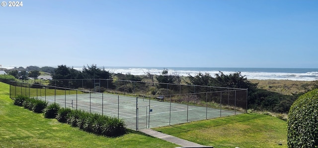 view of tennis court with a yard and a water view