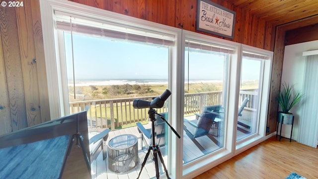 doorway to outside with wood-type flooring, a water view, and wood walls