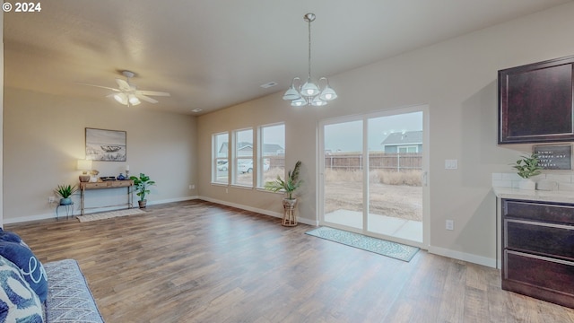 interior space with ceiling fan with notable chandelier, light wood finished floors, and baseboards